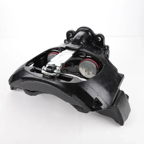A black brake caliper on top of a white surface.